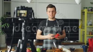 快乐有魅力的男人在家里用数码相机录制关于健康烹饪的视频食物